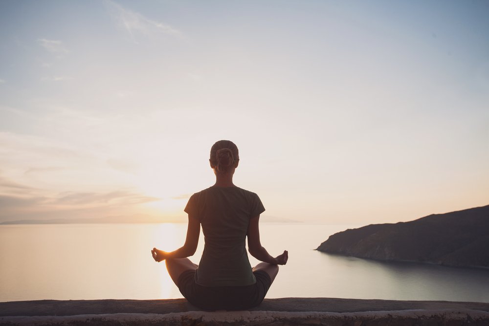 Woman doing Yoga - Meditation at Scenic View with Water and Mountain during Sunrise.